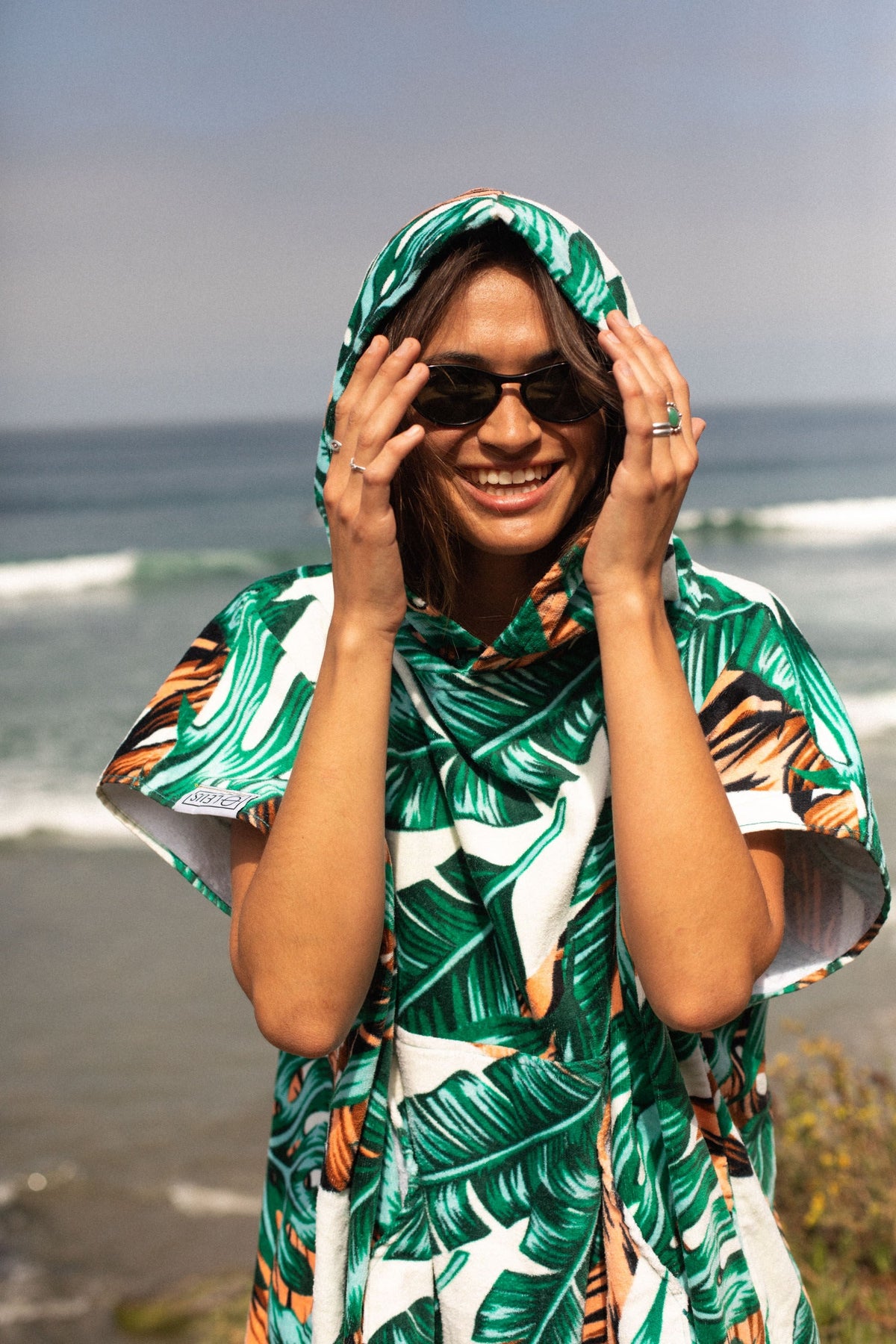 Jungle Fever Original Eco Poncho: woman hooded and smiling at the beach - Leus Towels Australia