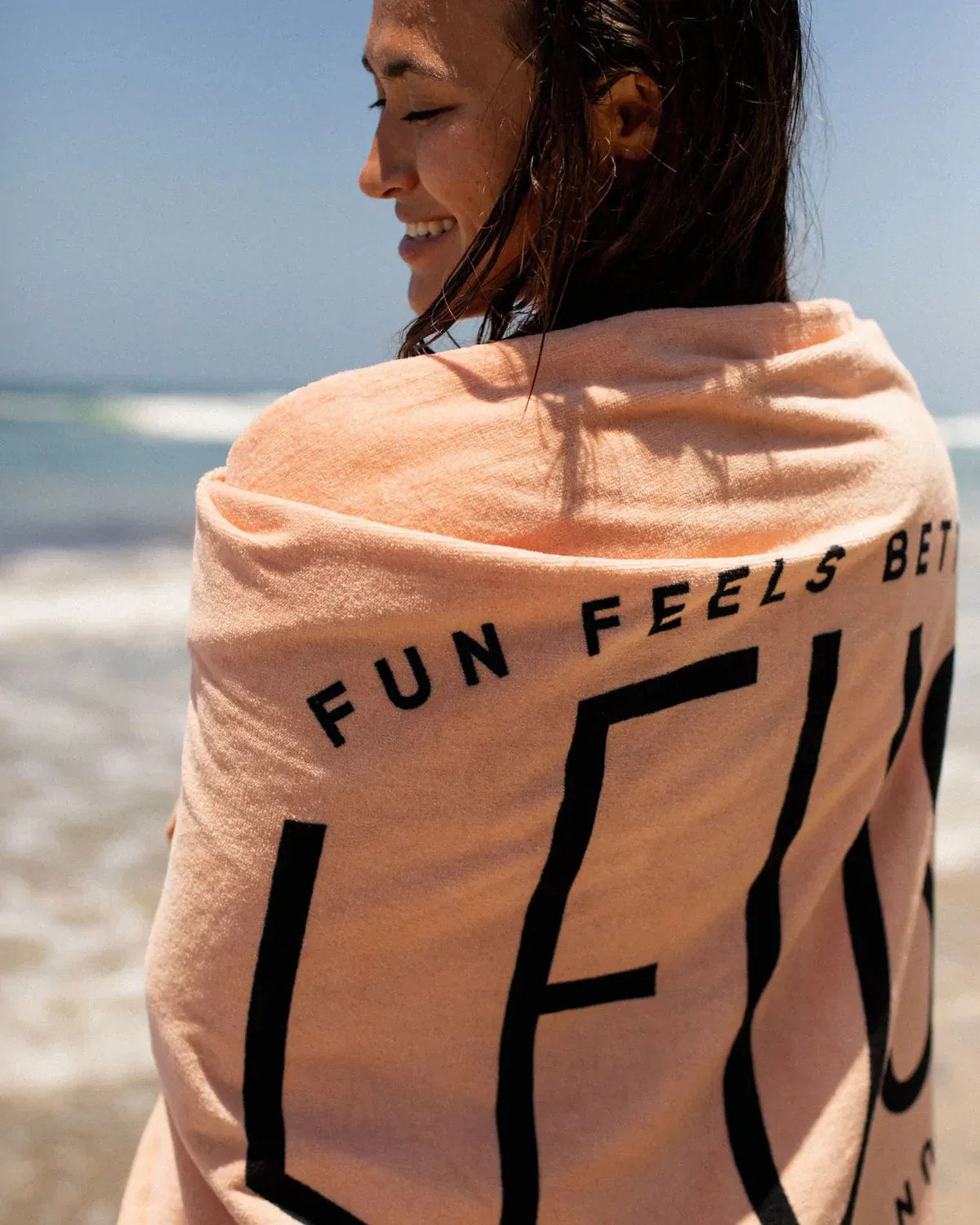 Happy Hour Beach Eco Towel: woman wrapped in the towel at the beach - Leus Towels Australia