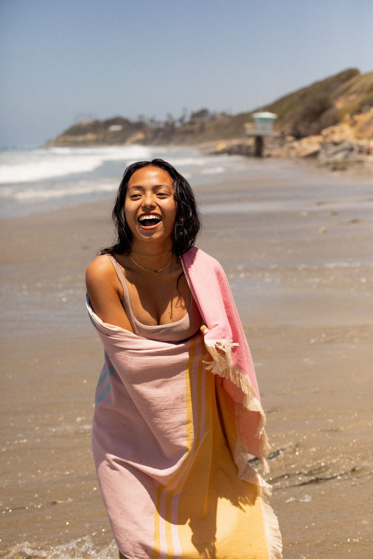 Zuma Turkish Eco Towel: woman wrapped and laughing at the beach - Leus Towels Australia