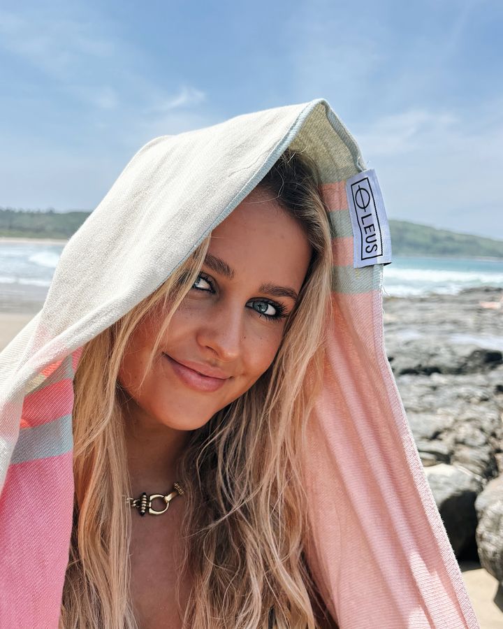Smiling woman wrapped in a LEUS Turkish towel at the beach